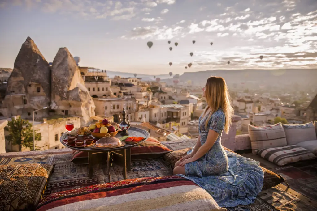 Una mujer se sienta en uno de los techos de Capadocia durante el amanecer temprano, cuando vuelan los globos | Qué Onda