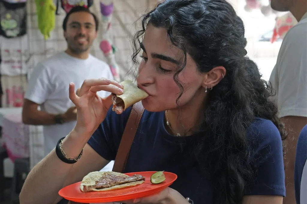 Clienta disfrutando de unos tacos en la Taquería El Califa de León CDMX | Qué Onda