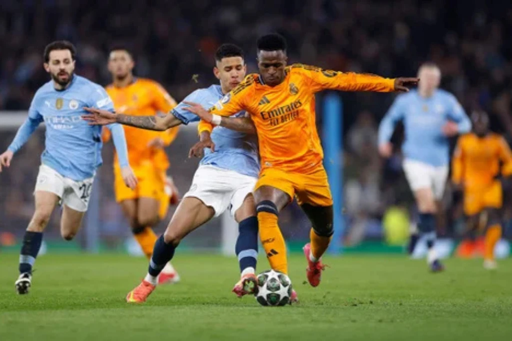 Vinicius Jr. trata de ganar la pelota a la última línea defensiva de los Citizens.