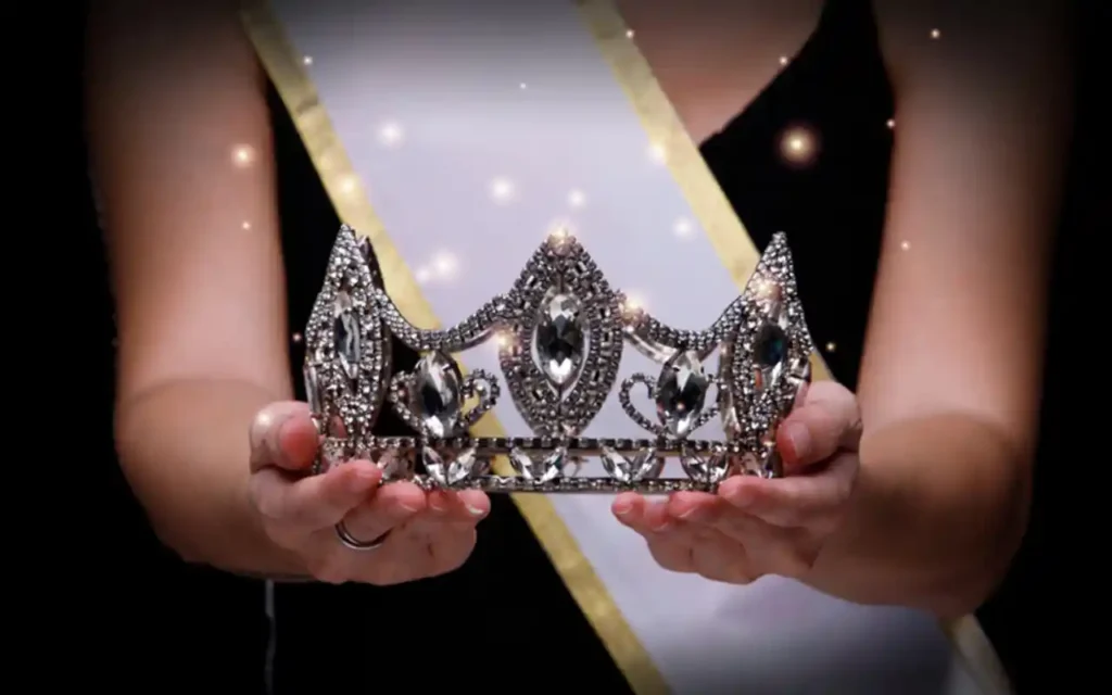 Una corona de reina de belleza sostenida con ambas manos, símbolo de fuerza interior y propósito  | Qué Onda