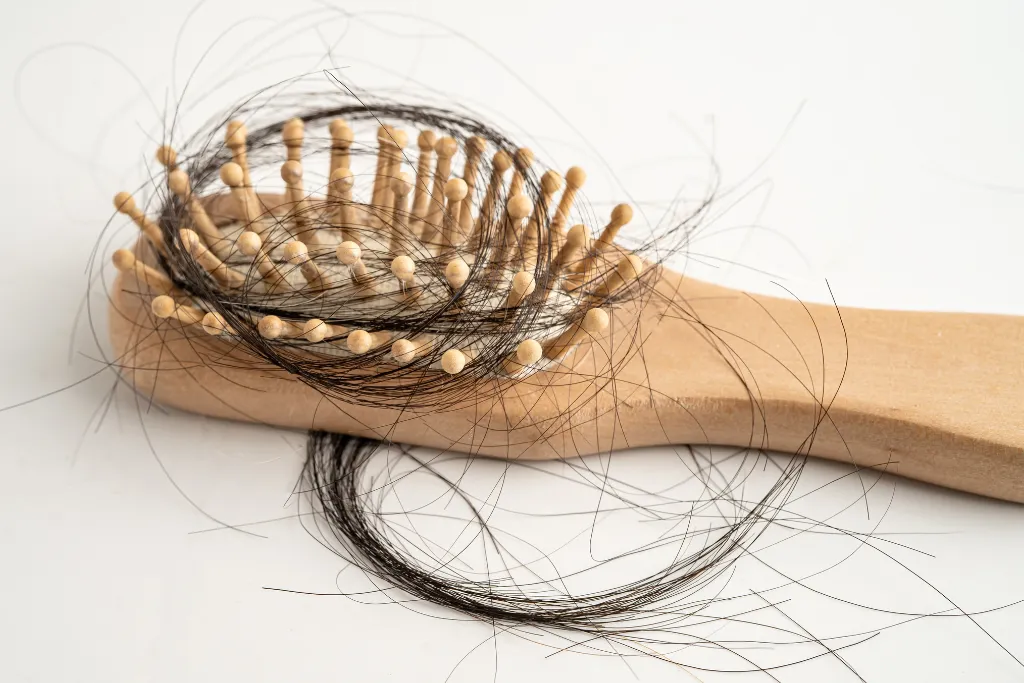Cepillo de madera con mechones de cabello atrapados entre las cerdas, representando la caída y pérdida del cabello | Qué Onda