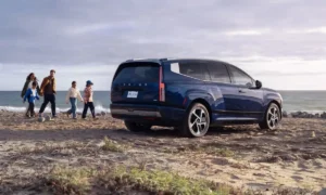 Hyundai IONIQ 9 2026 azul junto a una familia en la playa | Qué Onda
