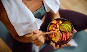 Salud Intestinal representada por una mujer comiendo un bowl de frutas y avena | Qué Onda