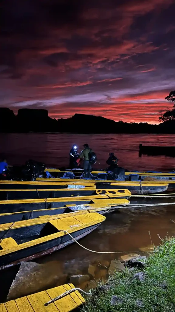 Viajar al Salto Ángel: curiaras tradicionales amarradas en la orilla del río bajo un impresionante cielo rojizo | Qué Onda